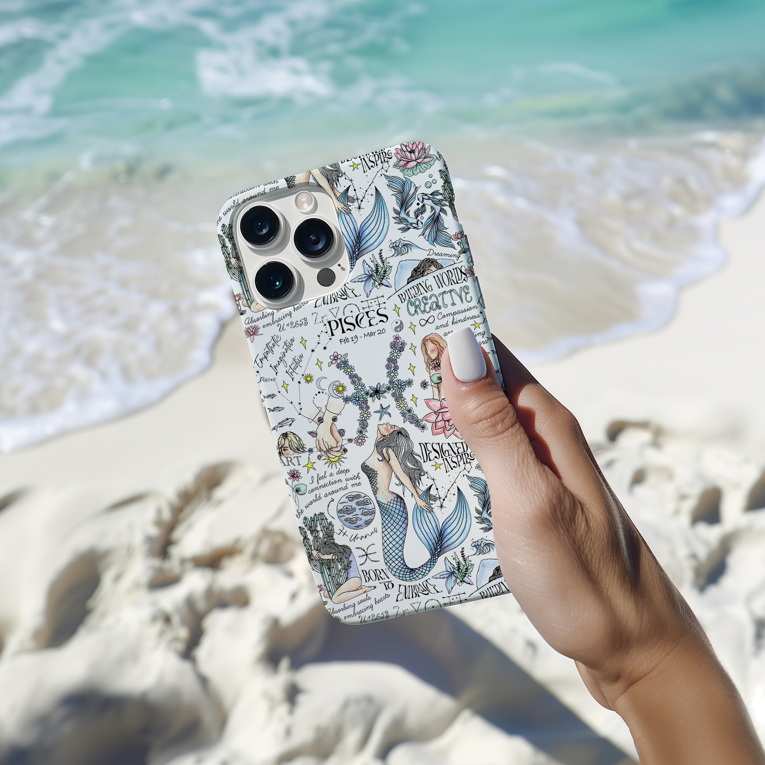 a person holding up a phone case in front of the ocean